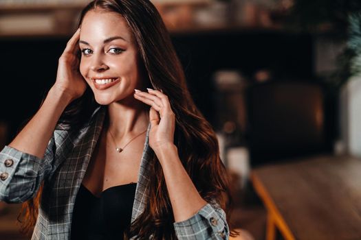 Portrait of a young European girl with long hair in a coffee shop in the evening light, a tall Girl in a jacket with long hair in a cafe.