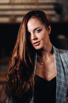 Portrait of a young European girl with long hair in a coffee shop in the evening light, a tall Girl in a jacket with long hair in a cafe.