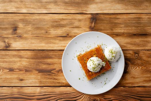 Turkish dessert kunefe served with ice cream on wooden background, close up