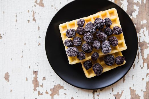 Belgian waffles with blackberry on an old wooden table.