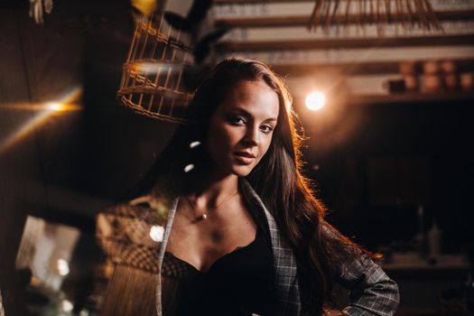 Portrait of a young European girl with long hair in a coffee shop in the evening light, a tall Girl in a jacket with long hair in a cafe.