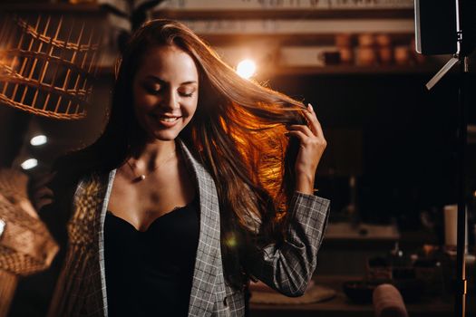 Portrait of a young European girl with long hair in a coffee shop in the evening light, a tall Girl in a jacket with long hair in a cafe.