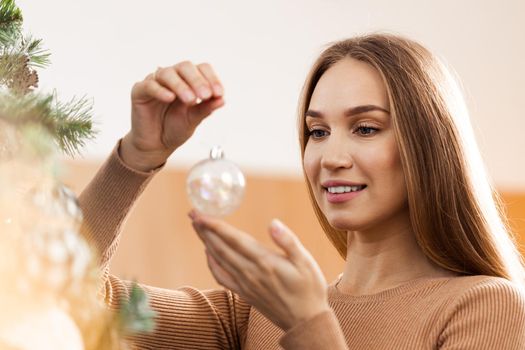 Closeup image of woman in sweater decorating Christmas tree