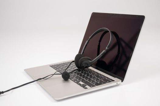 Headset on laptop keyboard on white background