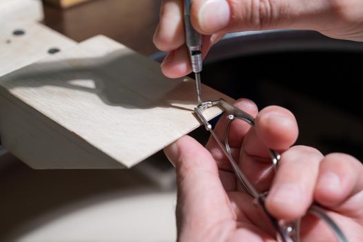 Optical technician fixing glasses. Close-up of male hands with screwdriver and goggles frame