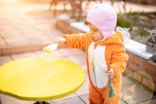 adorable little toddler paints illuminated yellow round table with brush