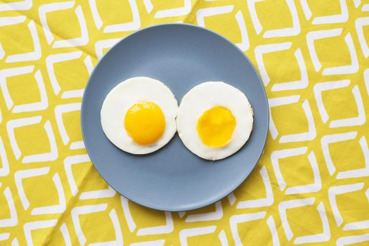 two eggs on a plate and a yellow napkin.