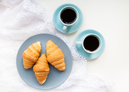 two cups of coffee with croissants on the background of laces, close-up