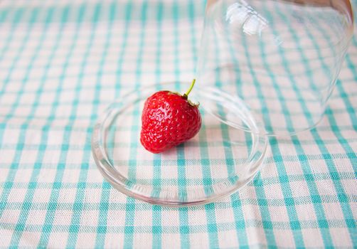 Strawberry on a glass plate and a napkin in a cell