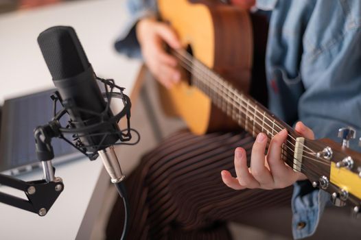 Faceless woman playing guitar and streaming live on laptop