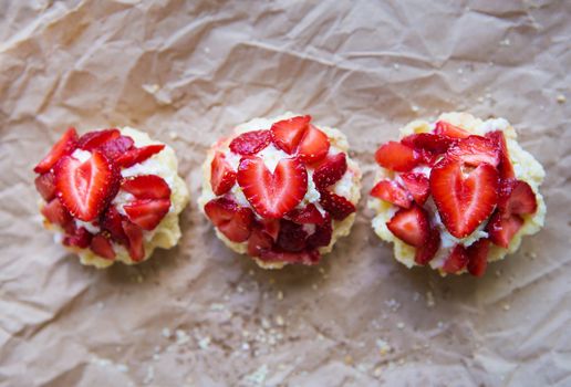 Very tasty muffins with fresh strawberries lie on kraft paper.