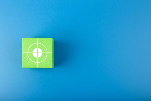Goal symbol on green toy cube against dark blue background. Concept of goal, success, reaching business and personal aims