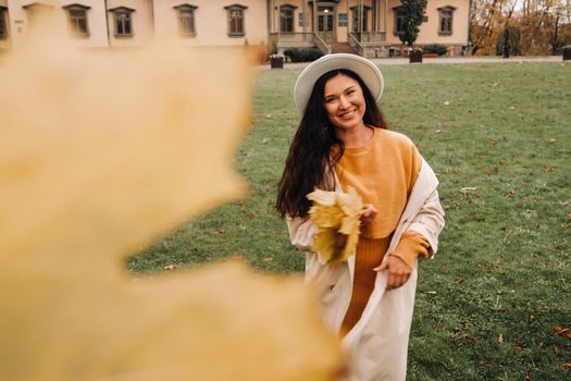 a girl in a white coat and hat smiles in an autumn Park.Portrait of a woman in Golden autumn