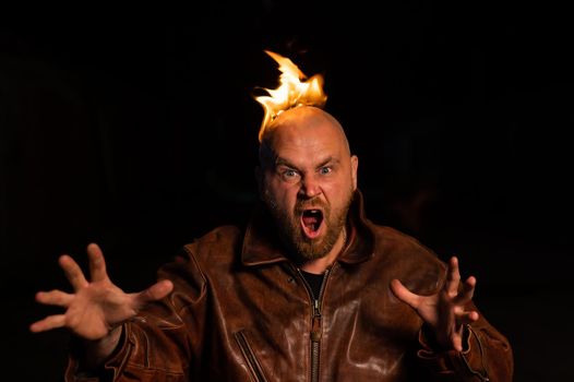 Bald man in a leather jacket with a burning head on a dark background