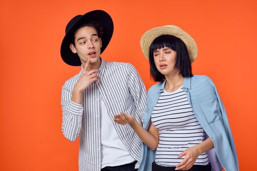 man and woman in hats posing fashion orange background. High quality photo