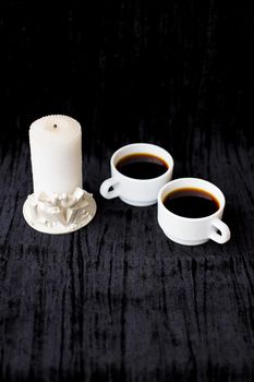 candle and two cups of coffee on a black background.