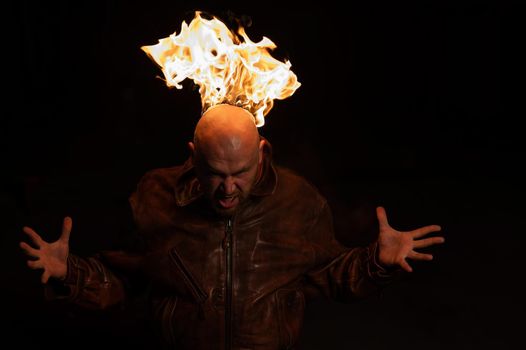 Bald man in a leather jacket with a burning head on a dark background