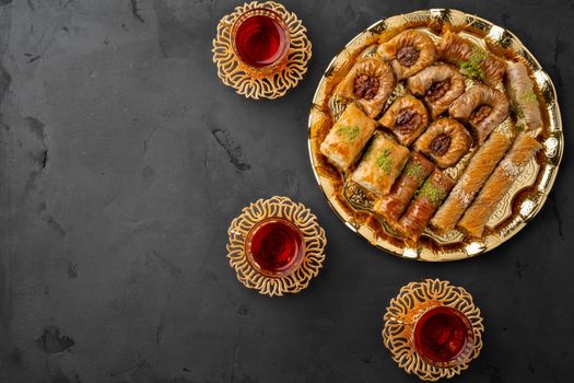 Turkish tea in traditional glasses baklava on black background, top view
