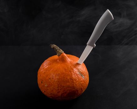 Knife in a pumpkin on a black background. Halloween symbol