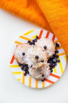 Blueberry muffins on a napkin and bright orange plate, close-up