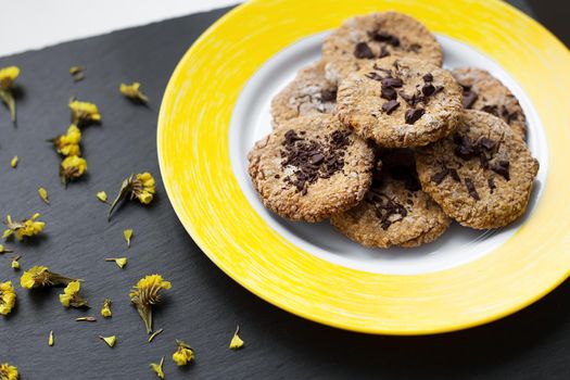 Oatmeal cookies with chocolate on bright yellow plate