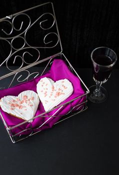 glass of wine and cookies in the form of heart lies in a casket