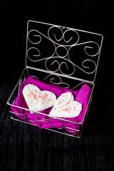 Cookies in the form of heart lies in a casket with pink cloth.
