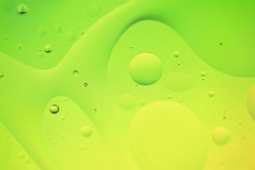 Oil drops in water. Defocused abstract psychedelic pattern image green and yellow gradient colored. DOF.