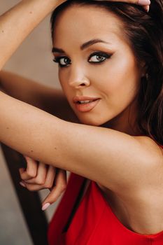 a brunette girl with long hair in a red dress poses in the studio.