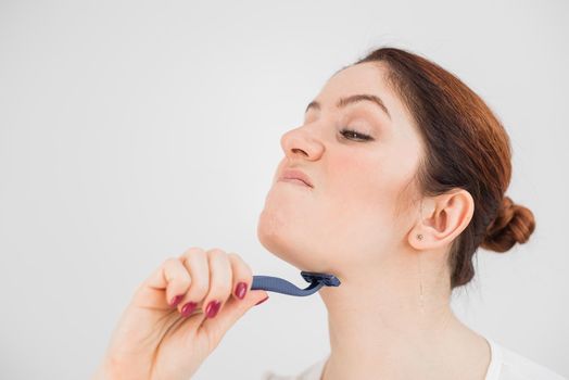 Caucasian funny woman shaves her face with a straight razor on a white background. Copy space