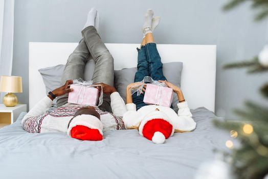 Joyful couple together in bed on Christmas morning. Caucasian woman and African American man celebrate Christmas together.