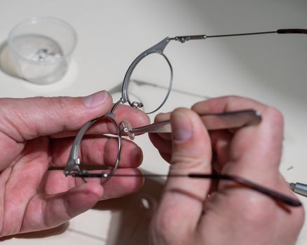 Installation of nose pads in glasses. A male technician repairs broken glasses.