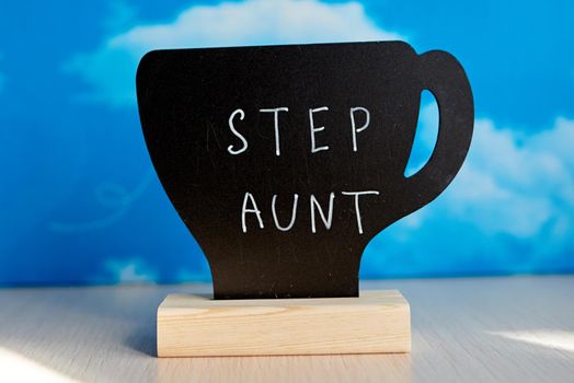 Chalk table tent with english word "Step aunt" written by white chalk marker. Blurred background, bokeh effect