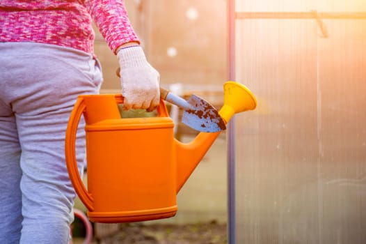 the gardener carries a watering can to the greenhouse/ no face close up. hobby concept