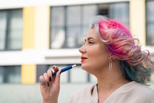 Caucasian woman with colored hair smokes an electronic cigarette