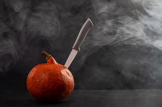 A knife in a pumpkin in the smoke. Happy Halloween