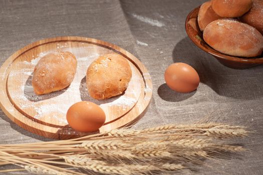 pies on a cutting board in flour, homemade baking buns, wheat ears