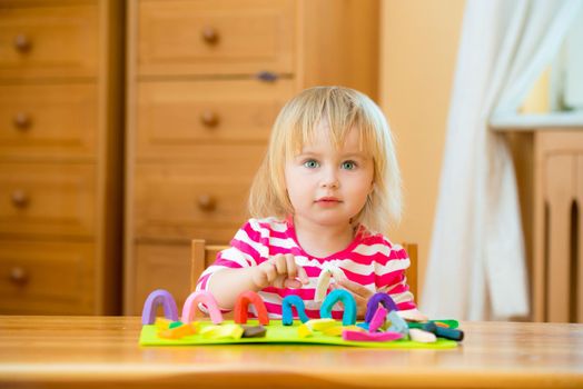 Cute Little girl playing with plasticine at home