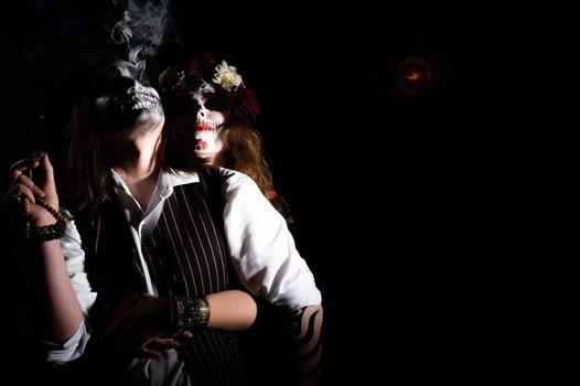 Woman in santa muerte costume and man in skeleton bodypainting for halloween