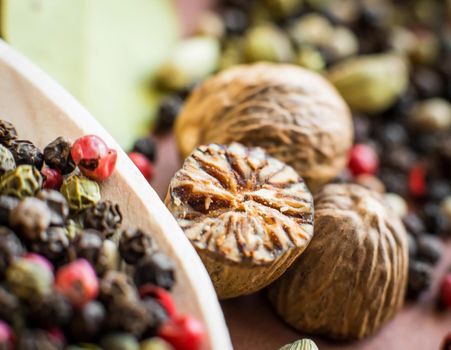 Nutmeg with broken part, peppers and other spices