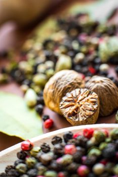 Nutmeg with broken part, peppers and other spices