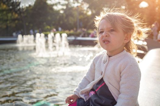 emotion disgust face. Grimacing toddler girl in the park