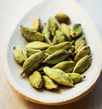 Whole cardamom in wooden spoon