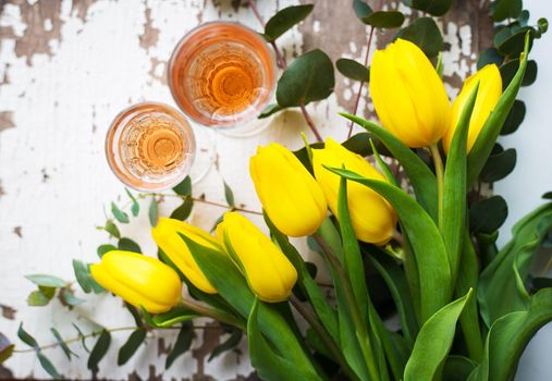 yellow tulips on a white table with glasses of rose wine