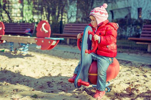 little cute girl playing at the playground in autumn