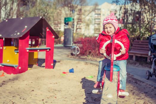 little cute girl playing at the playground in autumn