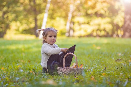 Toddler playing with witch hat in autumn sunny park