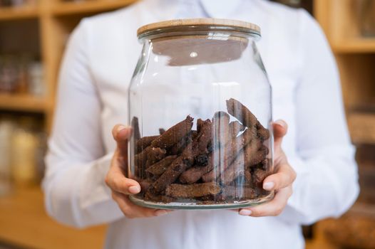 A woman holds croutons in a glass jar. Eco shop without plastic waste