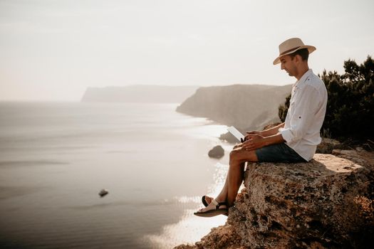 freelancer businessman working remotely on laptop at the beach near the sea