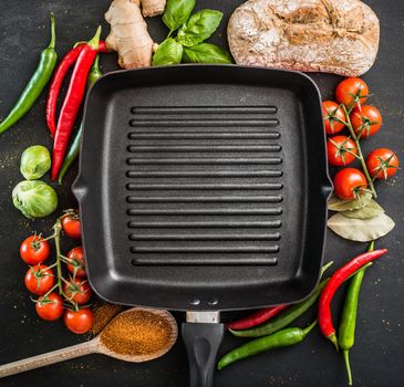 Cast iron griddle pan on black background with vegetables